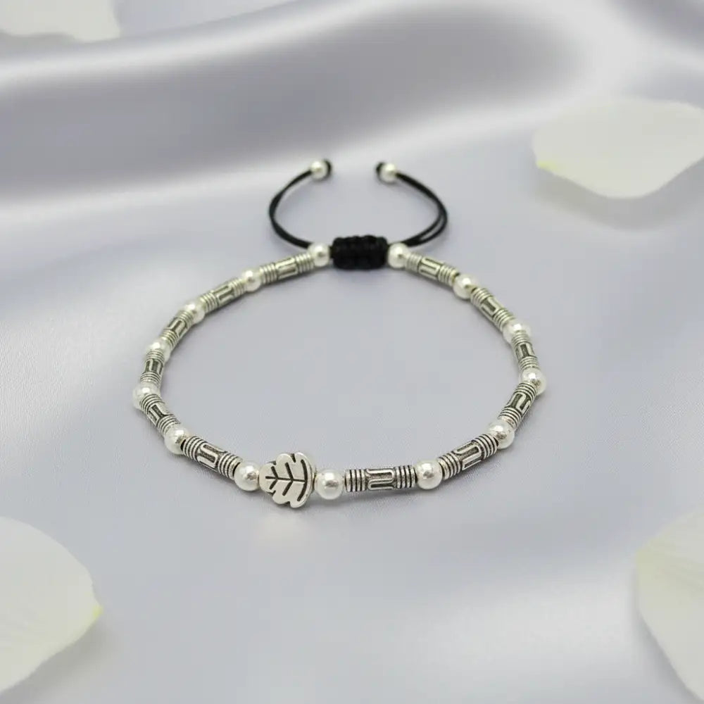 Bracelet with white beads and black cord on a light gray background