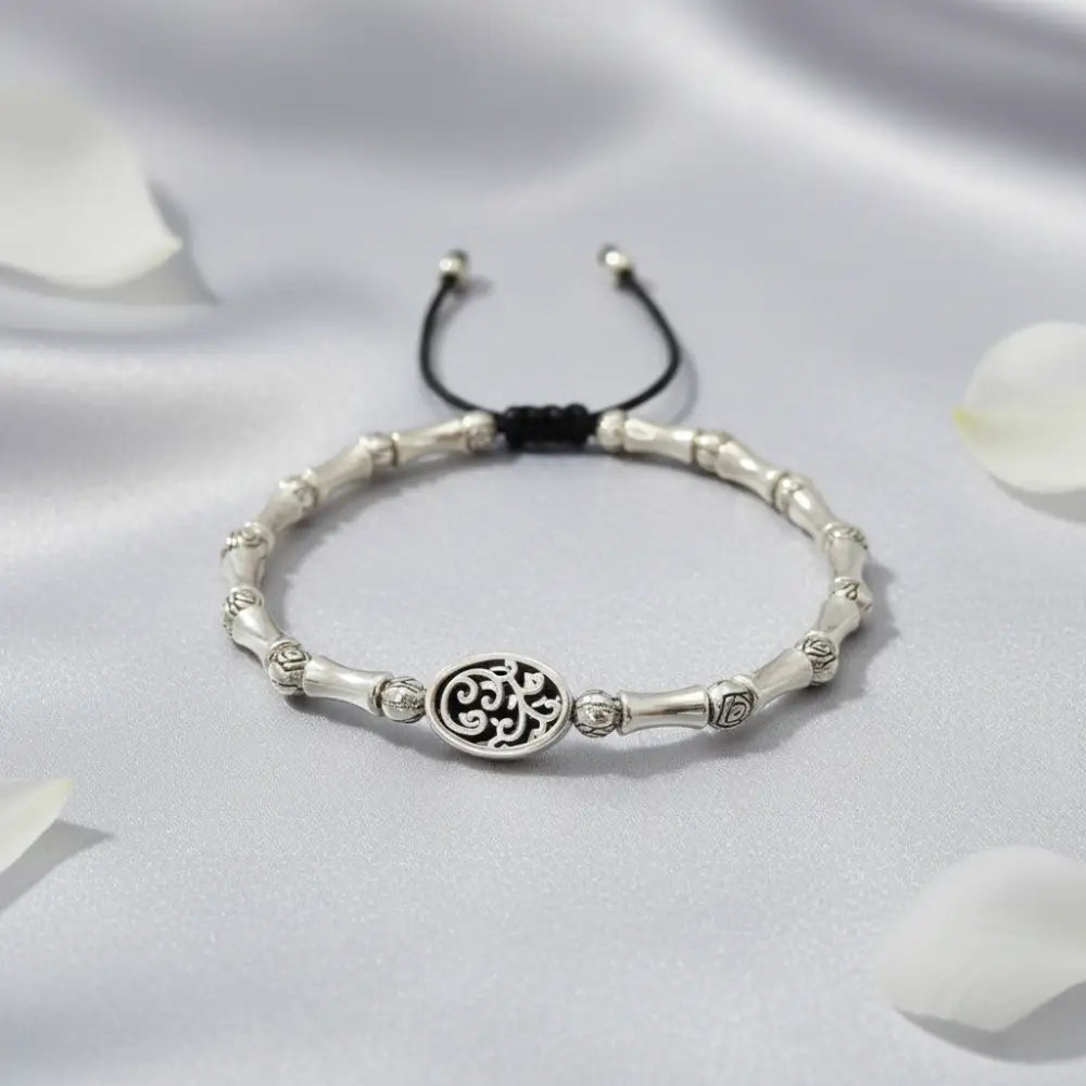 Silver bracelet with a central circular design on a white fabric background