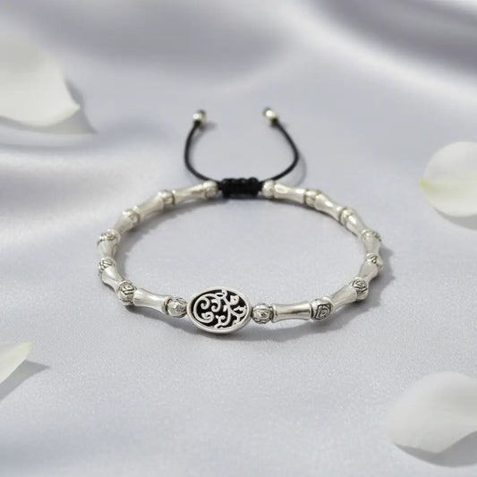 Silver bracelet with a central circular design on a white fabric background