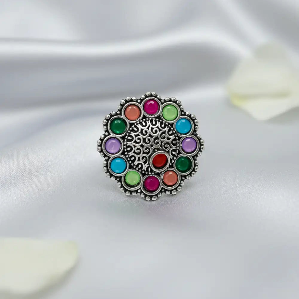 Multicolored gemstone ring on a white fabric background