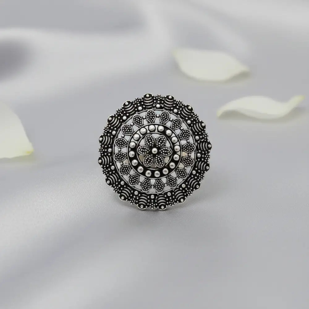 Silver ring with intricate design on a light gray background