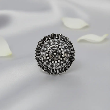 Silver ring with intricate design on a light gray background