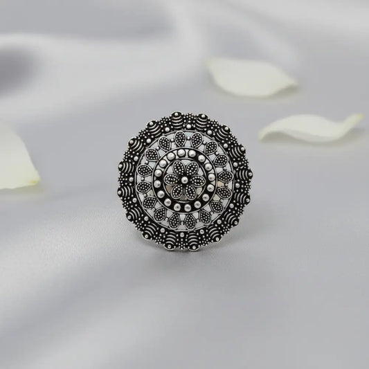 Silver ring with intricate design on a light gray background