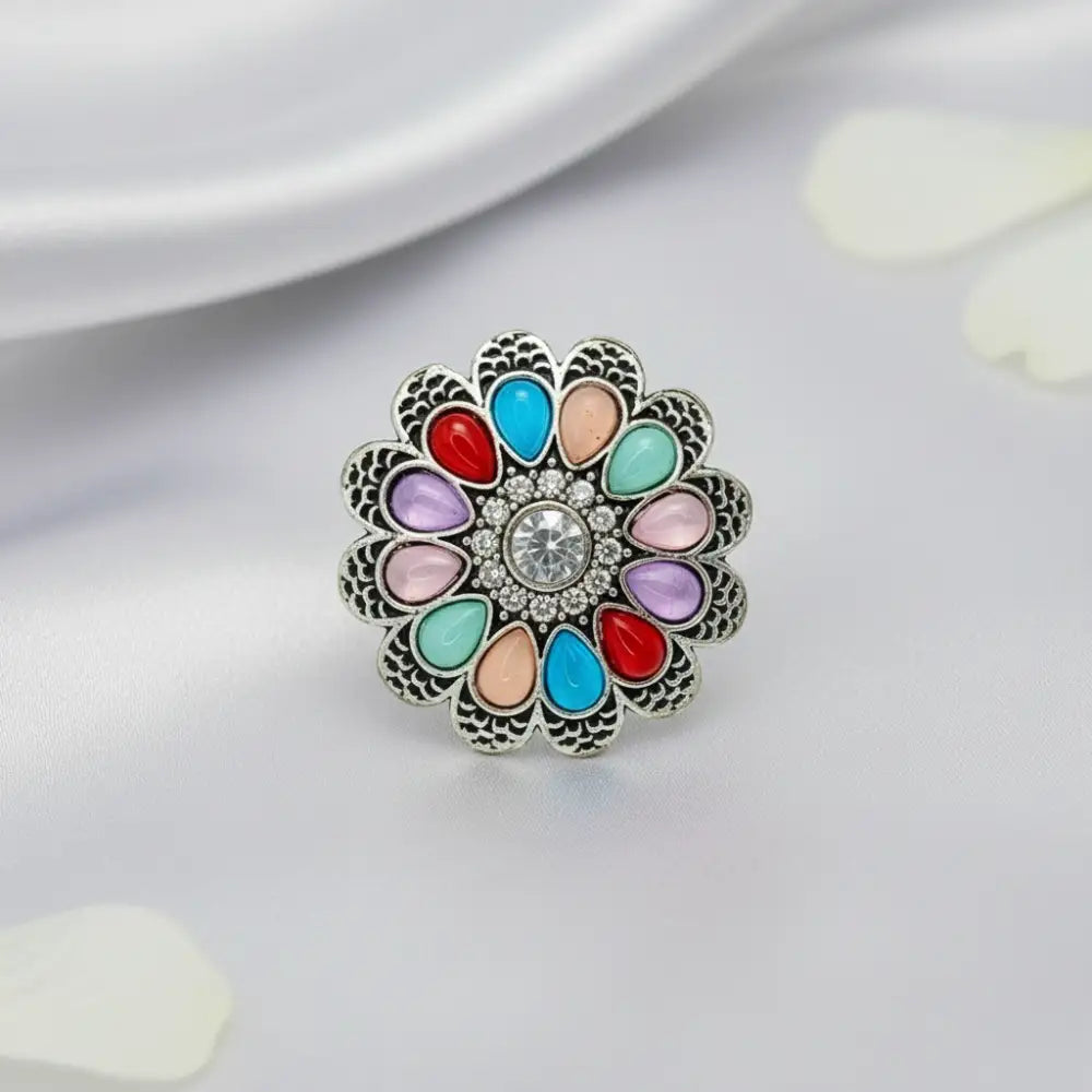 Multicolored floral brooch with a central gemstone on a light background