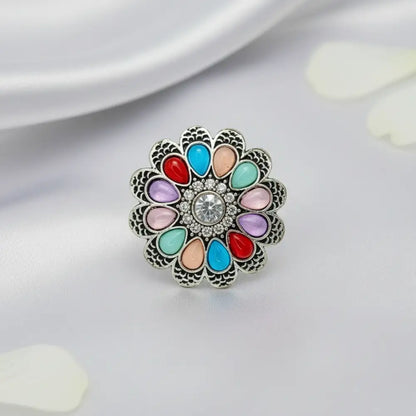 Multicolored floral brooch with a central gemstone on a light background