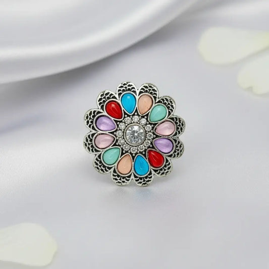 Multicolored floral brooch with a central gemstone on a light background