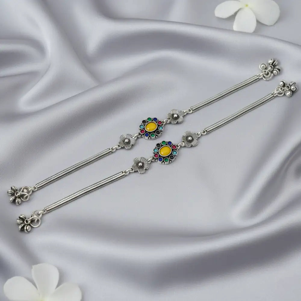 Silver earrings with colorful gemstones on a satin background