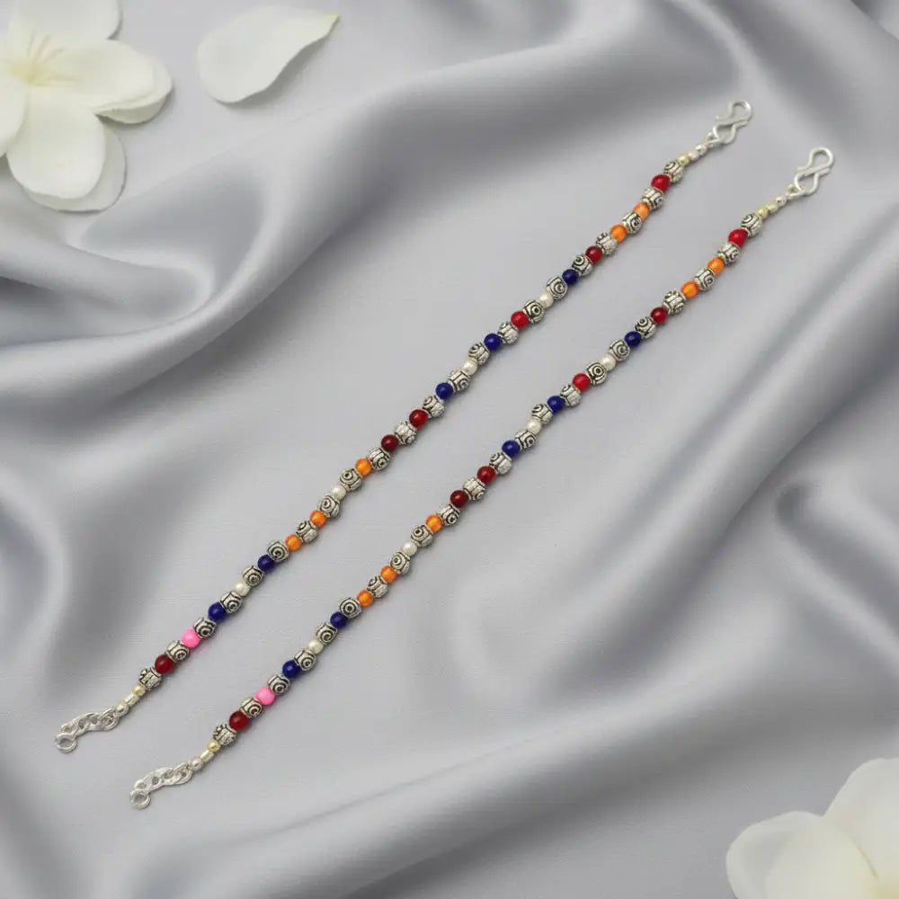 Two beaded bracelets on a satin surface with white flowers.