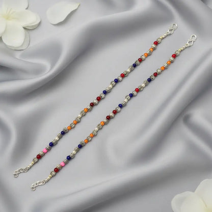 Two beaded bracelets on a satin surface with white flowers.