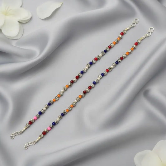Two beaded bracelets on a satin surface with white flowers.