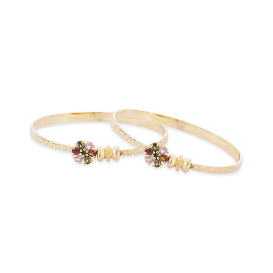 Pair of gold bangles with floral designs on a white background