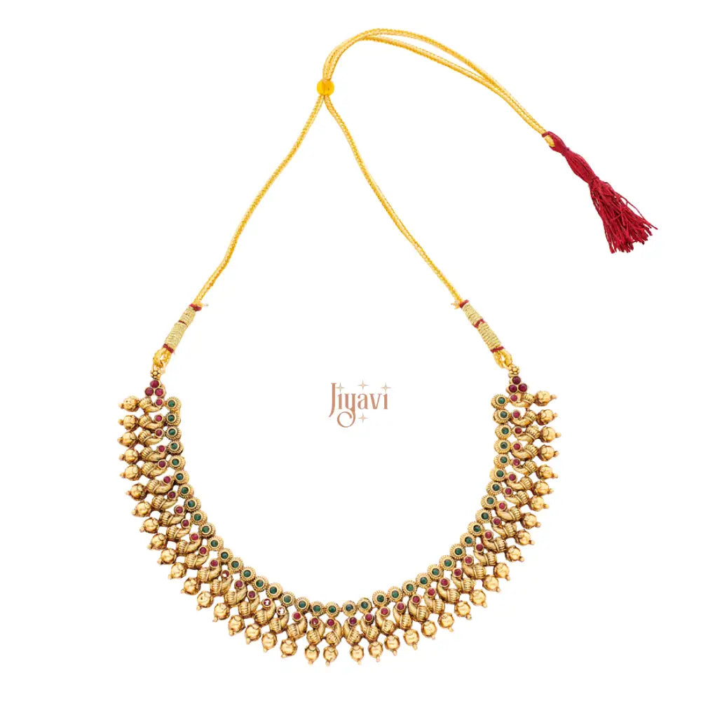 Gold necklace with beads and a red tassel on a white background, featuring the brand 'Jiyavi'.