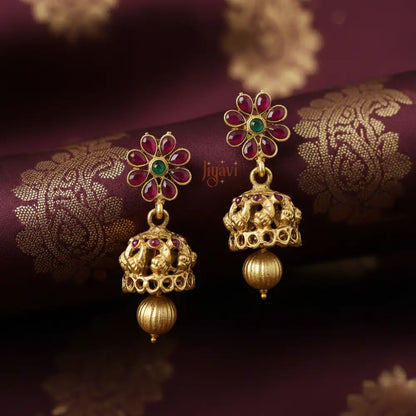 Gold earrings with gemstones on a purple fabric background
