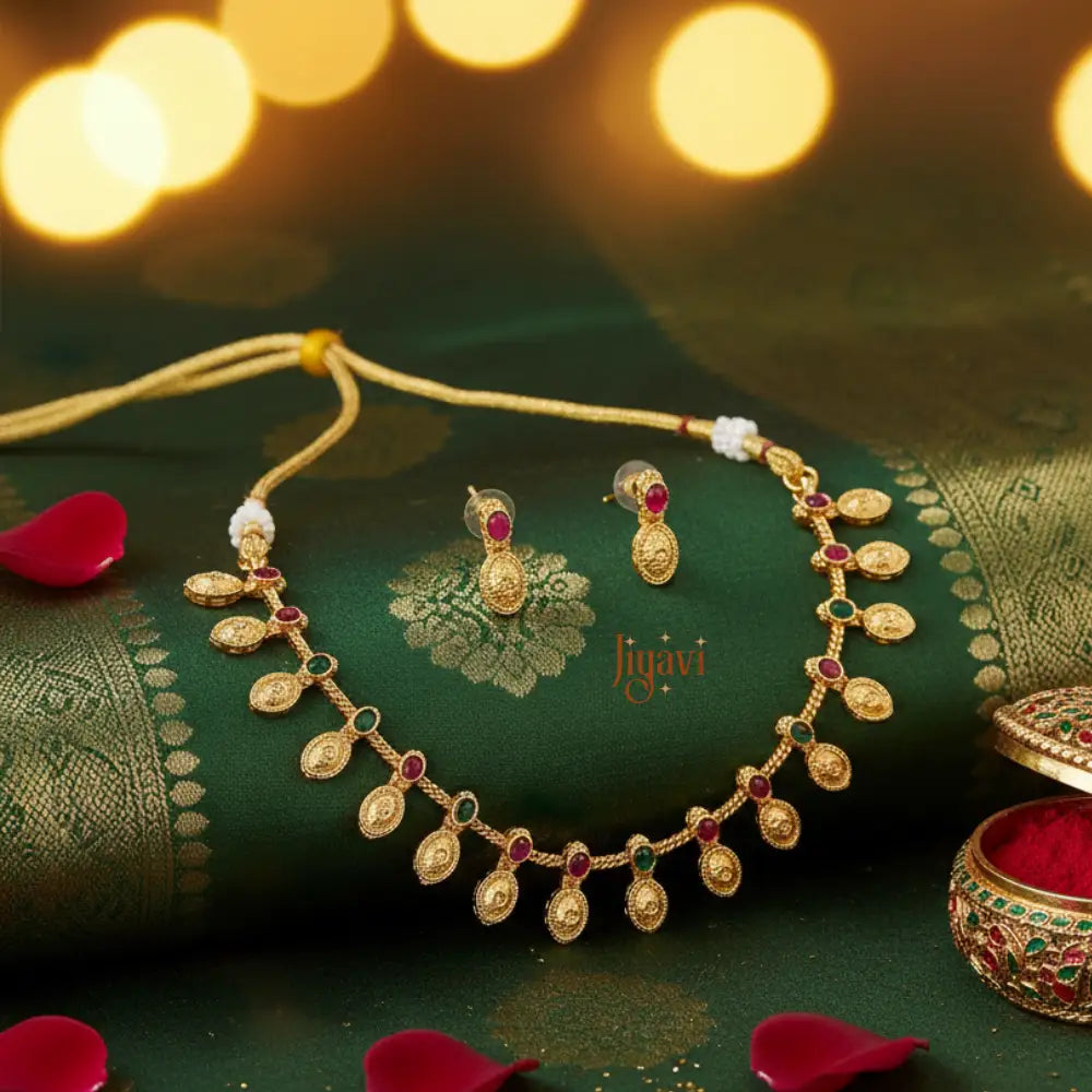 Gold necklace and earrings on a green fabric background with 'Jiyavi' branding.