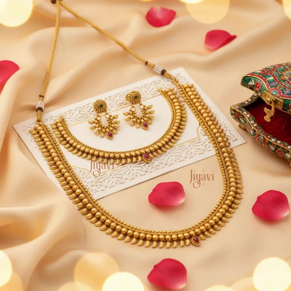 Gold necklace and earrings on a beige fabric background with 'Jiyavi' branding.