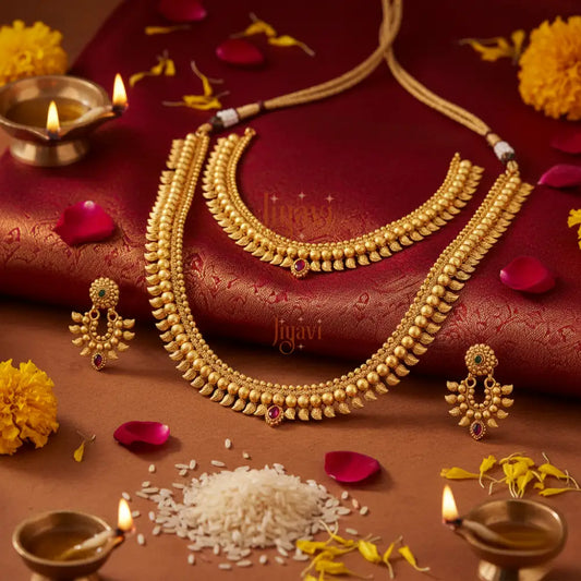Gold necklace and earrings on a red fabric background with decorative elements.