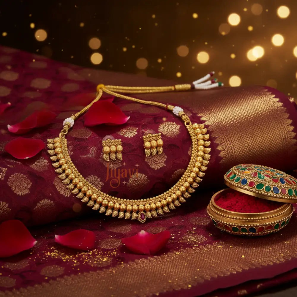 Gold necklace and earrings on a red fabric background with decorative elements