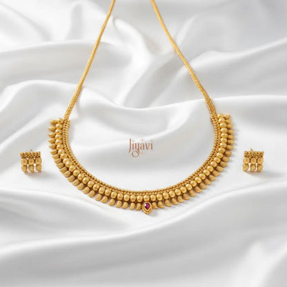 Gold necklace and earrings set on a white fabric background with 'Jiyavi' branding.