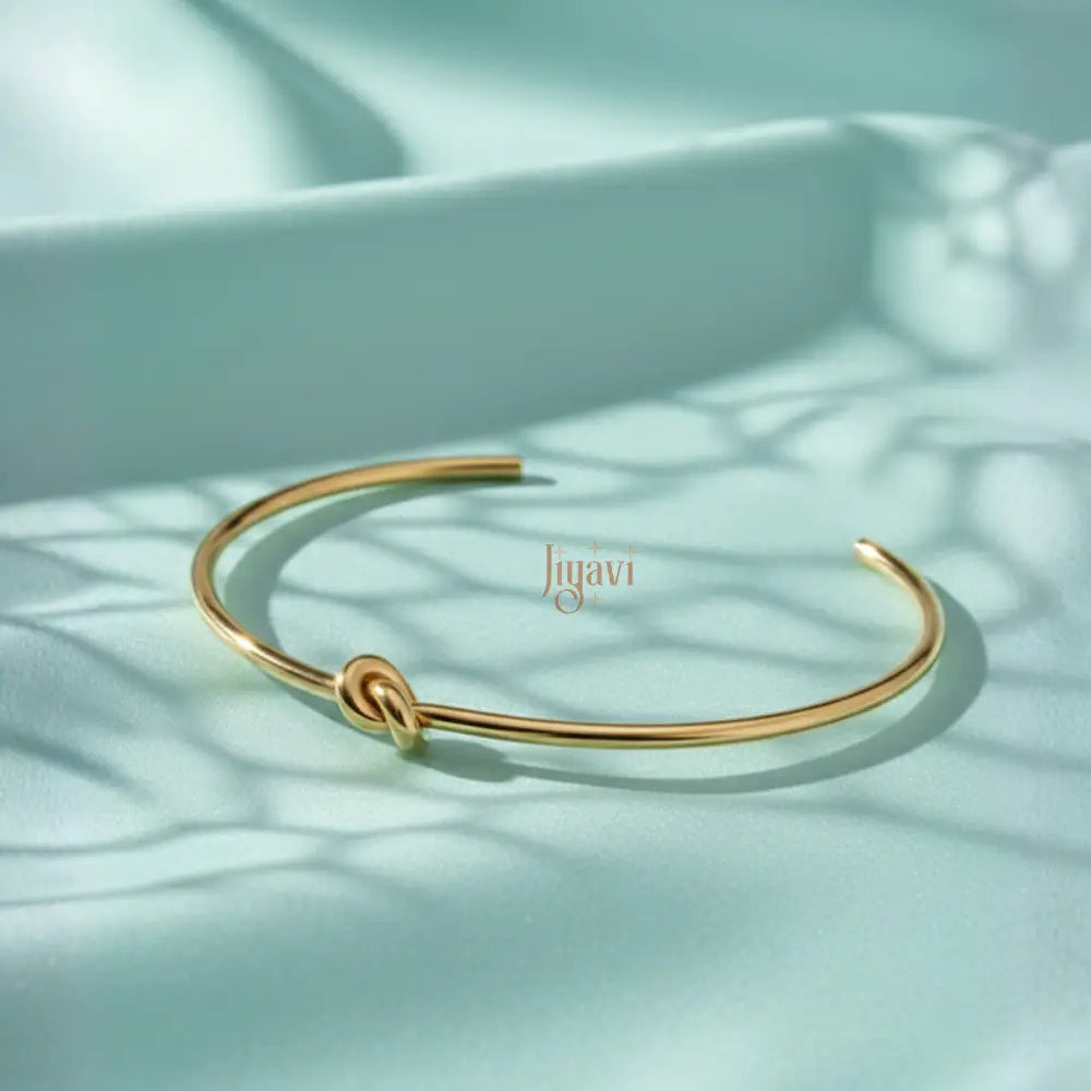 gold-plated, open cuff bangle bracelet with a knot design on cyan color satin