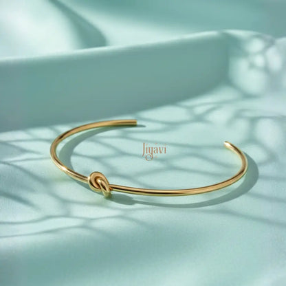 gold-plated, open cuff bangle bracelet with a knot design on cyan color satin