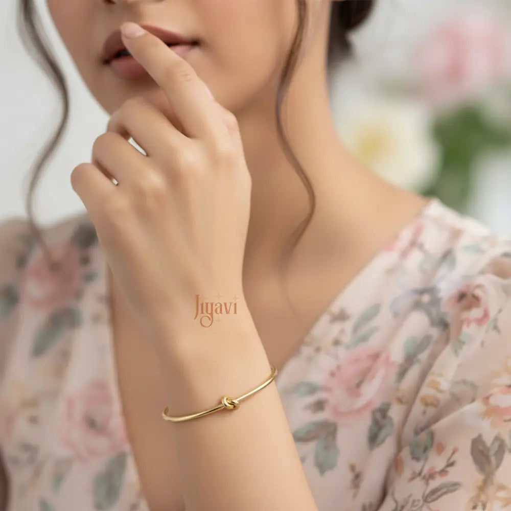 A girl wearing floral dress and gold plated, bracelet with a knot design