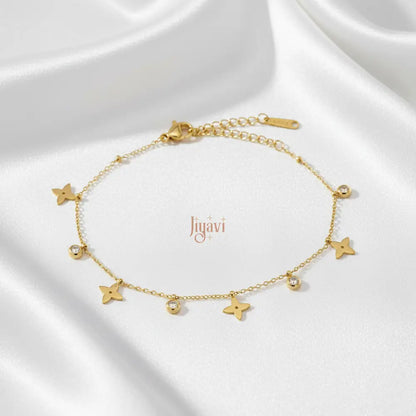 A delicate gold-plated chain bracelet adorned with several four-petal flower charms and small, sparkling clear stone on white satin
