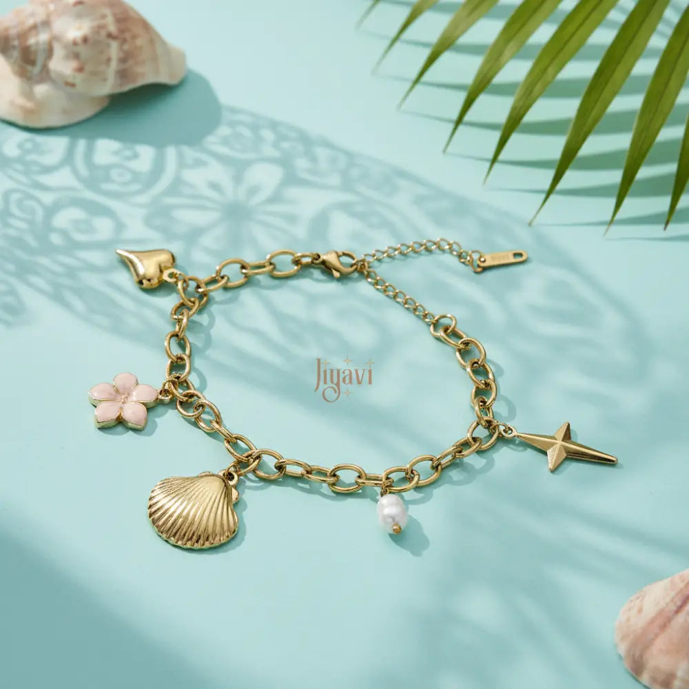 Gold bracelet with charms on a light blue background with shells and leaves.