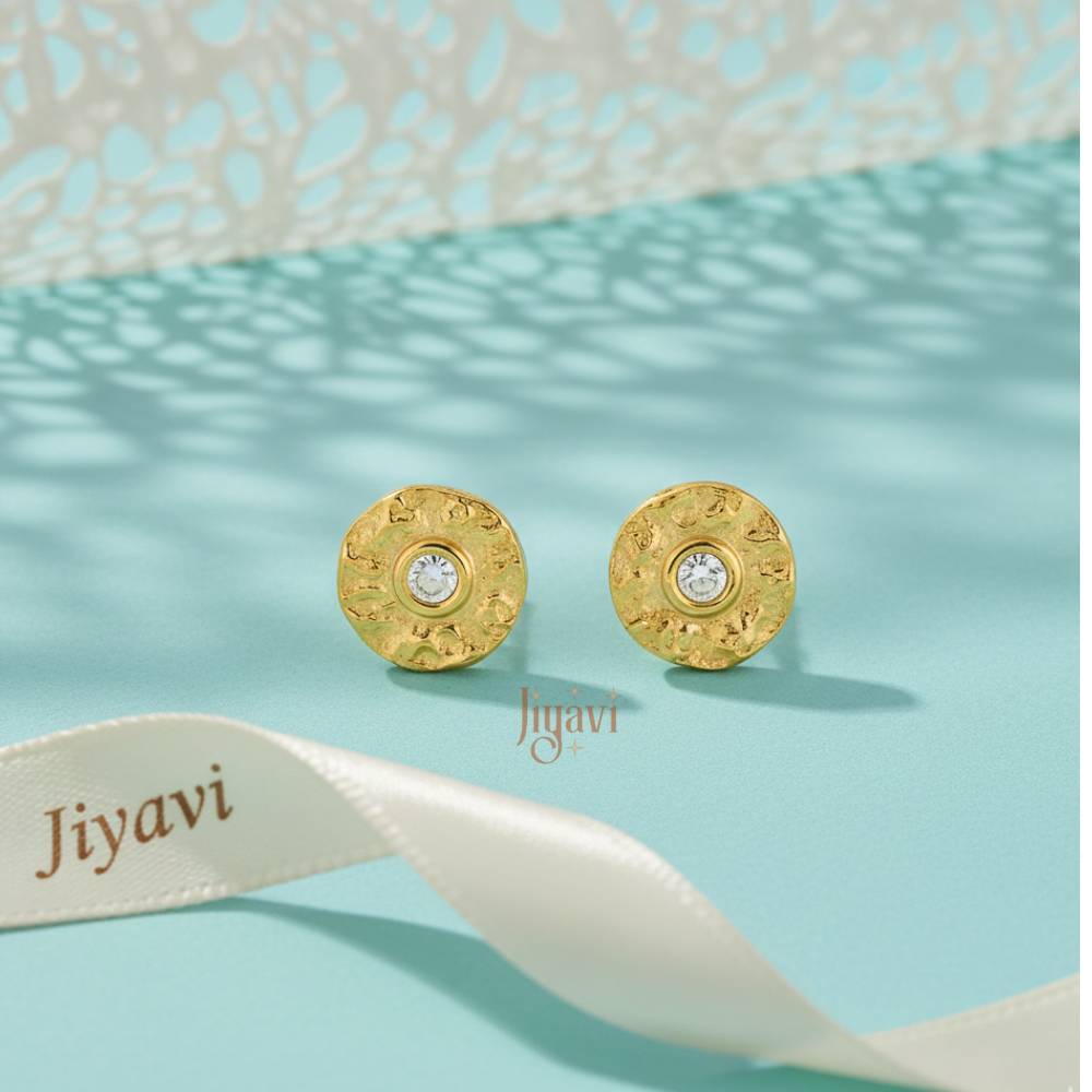 Gold earrings with a central gemstone on a light blue background with 'Jiyavi' branding.