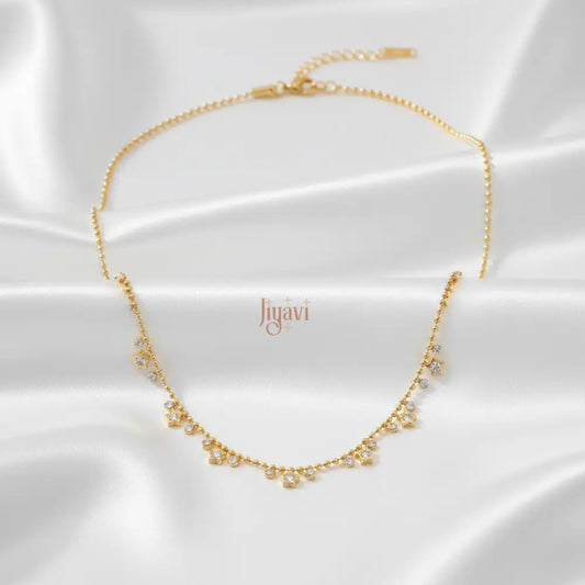 Gold necklace with small pearls on a white satin background, featuring the brand 'liyavi'.