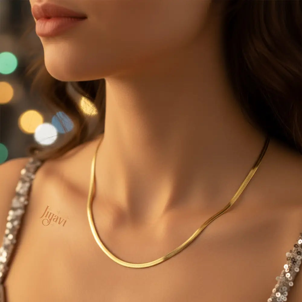 Gold necklace worn by a person with blurred lights in the background