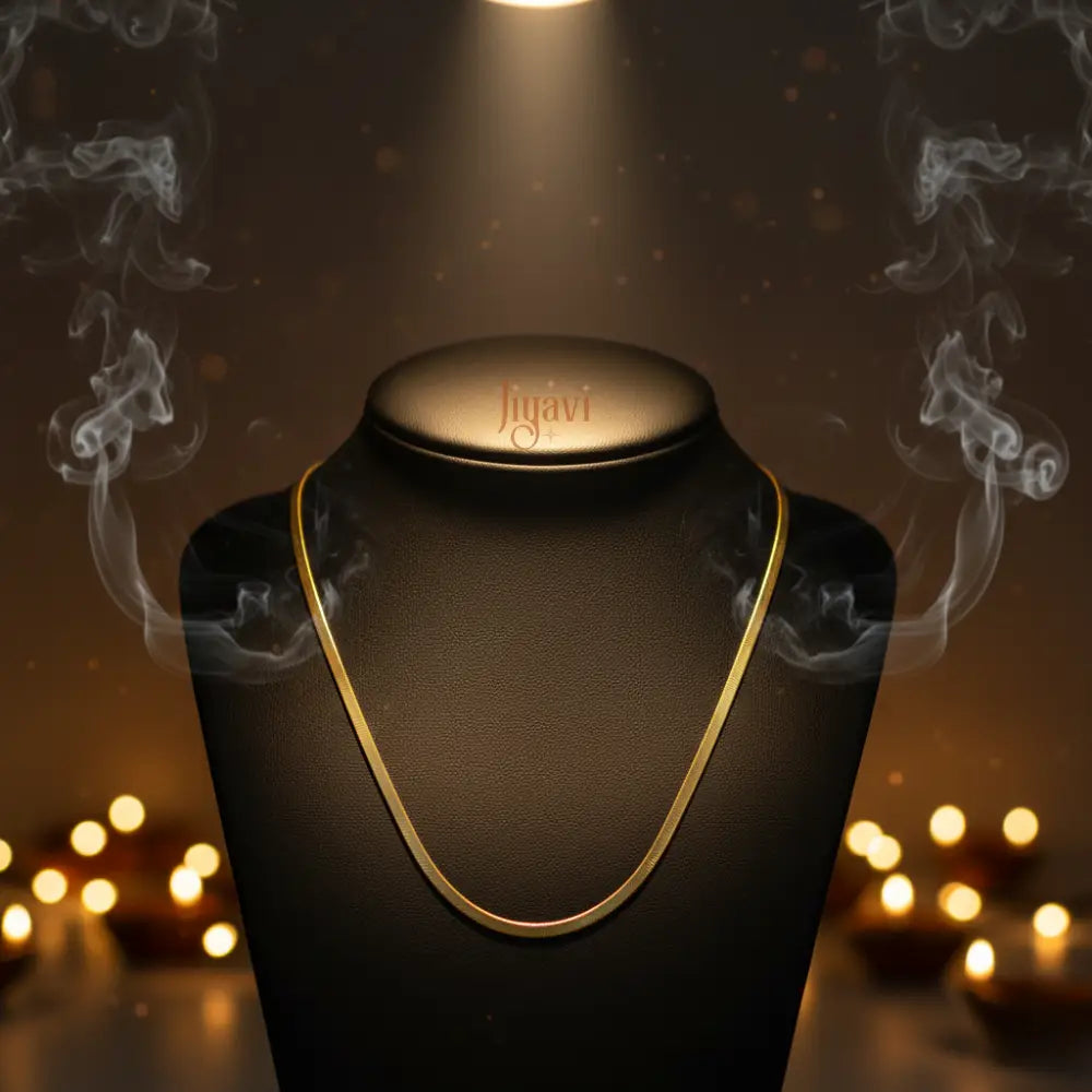 Gold necklace on a black stand with 'figari' branding, illuminated by a spotlight against a warm, blurred background.