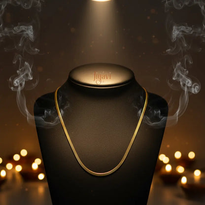 Gold necklace on a black stand with 'figari' branding, illuminated by a spotlight against a warm, blurred background.
