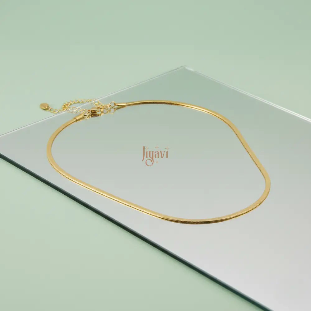 Gold necklace on a light green card with 'Jiguavi' branding