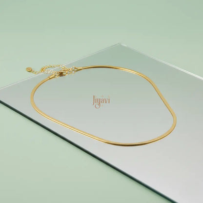 Gold necklace on a light green card with 'Jiguavi' branding