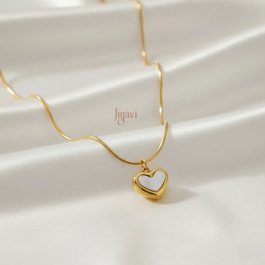 Gold necklace with a heart-shaped pendant on a white fabric background, featuring the brand 'liyavi'.