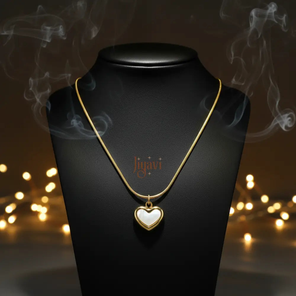 Gold necklace with a heart-shaped pendant on a black stand with blurred lights in the background