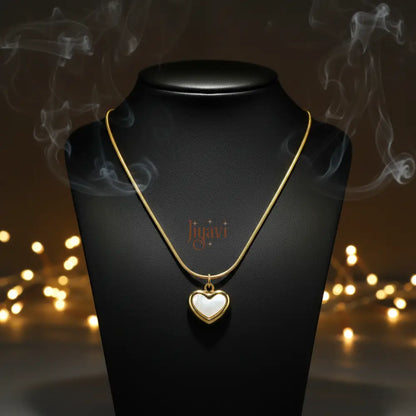 Gold necklace with a heart-shaped pendant on a black stand with blurred lights in the background
