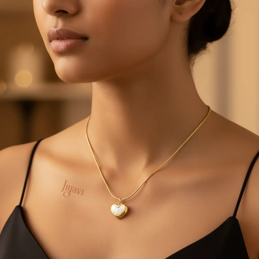 Woman wearing a gold necklace with a heart pendant, brand 'Jewelry' visible.