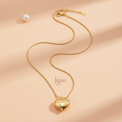Gold necklace with heart pendant and pearl on a beige background, featuring the brand 'Jugavi'.
