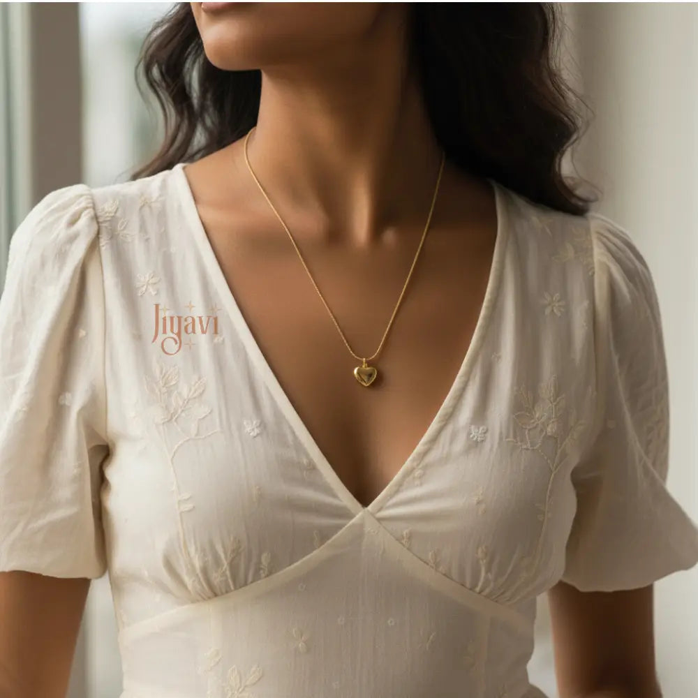 Woman wearing a white dress with 'Jugava' branding and a gold necklace.