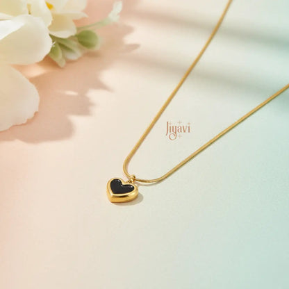 Gold necklace with a heart-shaped pendant on a soft background, featuring the brand 'Jugavi'.