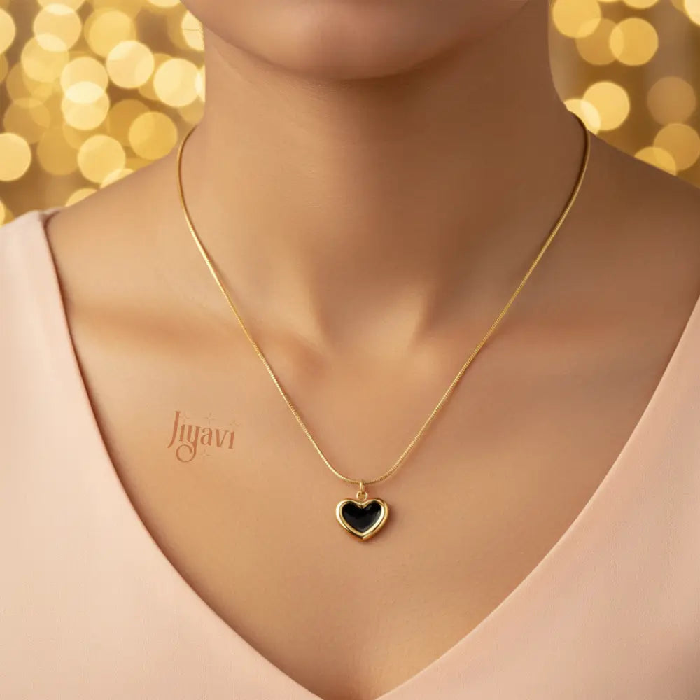 Gold necklace with a heart pendant on a model against a blurred golden background