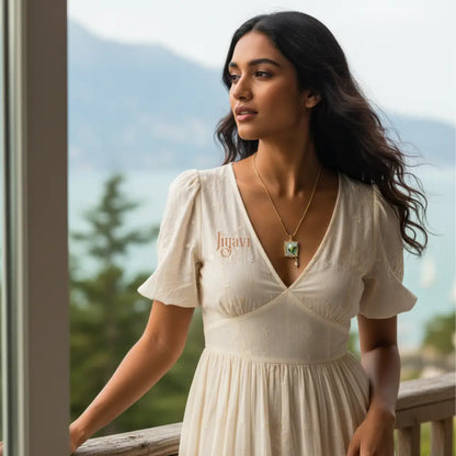 Woman in a white dress with 'Jiyavi' branding, standing outdoors with mountains in the background.