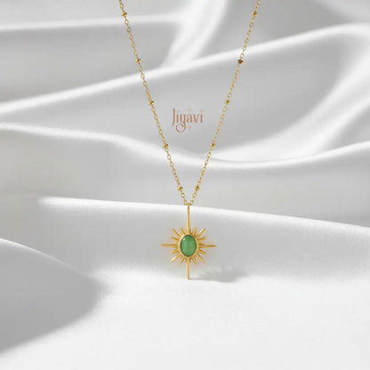 Gold necklace with a green pendant on a white fabric background