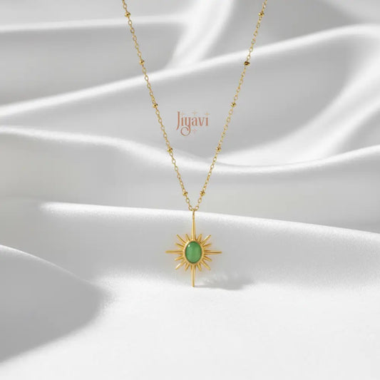Gold necklace with a green pendant on a white fabric background