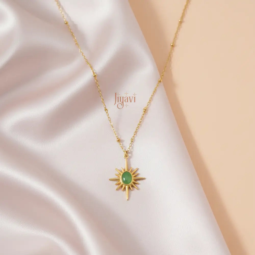 Gold necklace with a green pendant on a soft fabric background