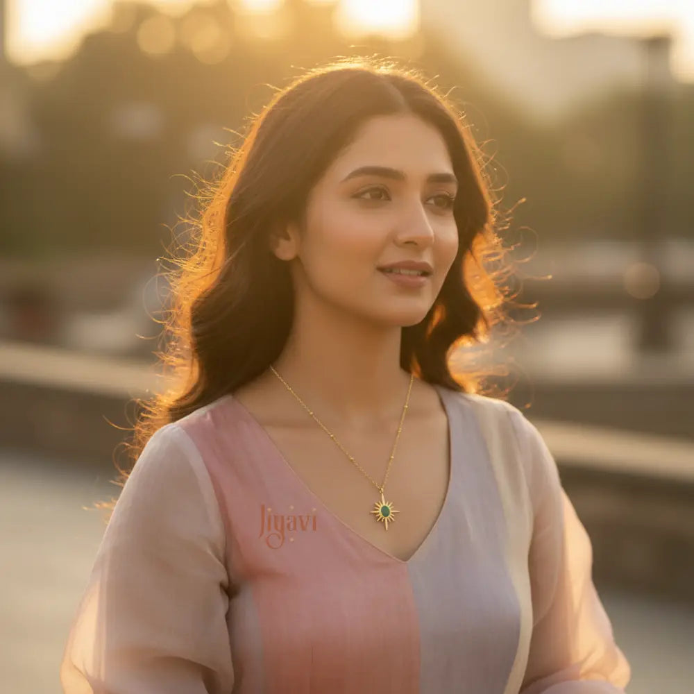 Woman wearing a pink and white outfit with a necklace, standing outdoors with a blurred background