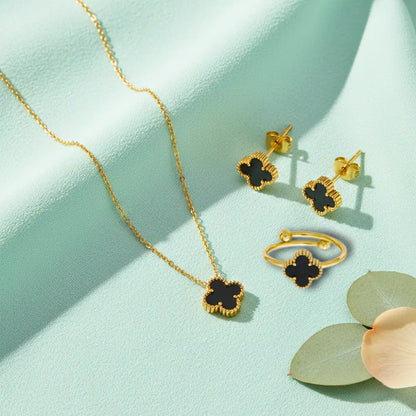 Gold jewelry set with black clover designs on a light green background