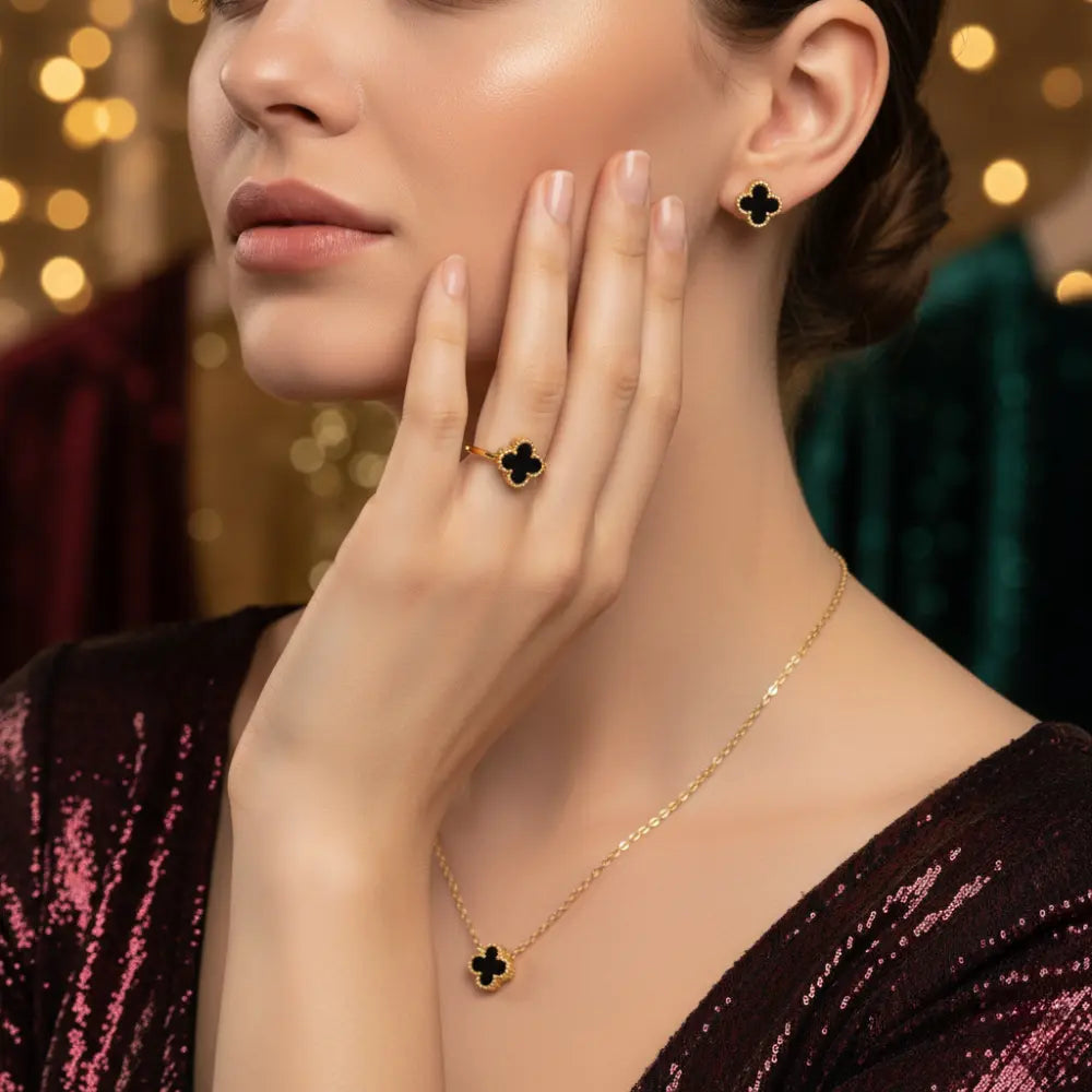 Woman wearing a gold necklace and clover-shaped earrings with a blurred background