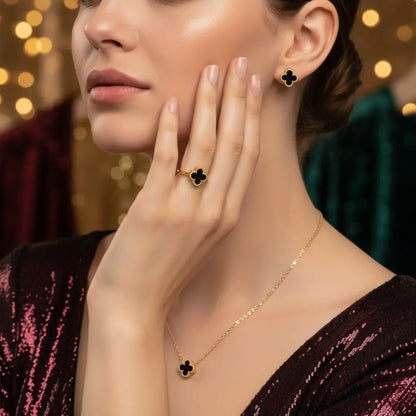 Woman wearing a gold necklace and clover-shaped earrings with a blurred background